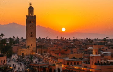 Things to Do in Marrakech– panoramic view of Marrakech Medina with Koutoubia Mosque and Atlas Mountains at sunset.
