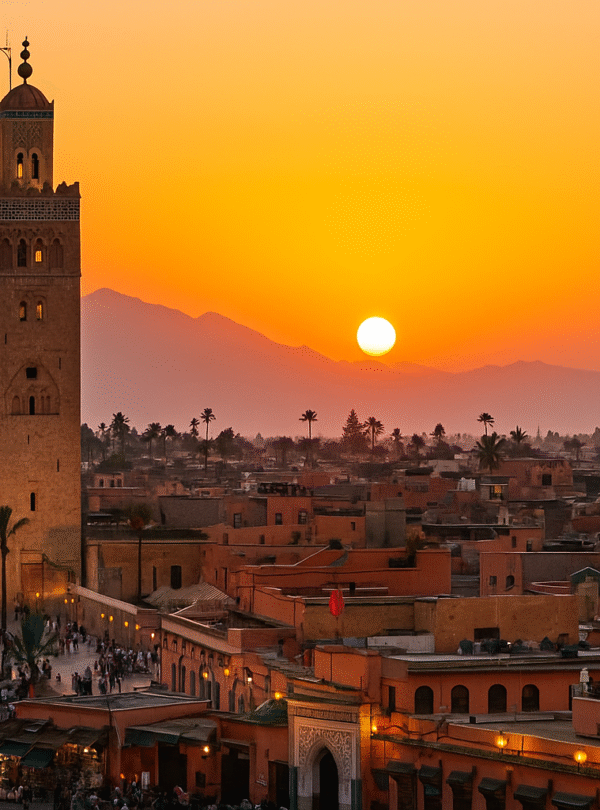 Things to Do in Marrakech– panoramic view of Marrakech Medina with Koutoubia Mosque and Atlas Mountains at sunset.